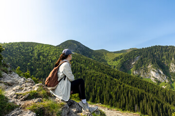 girl tourist sits on the edge of a cliff enjoying the view of the mountains and valley. travel and hiking in the mountains, Tatra Mountains, Poland