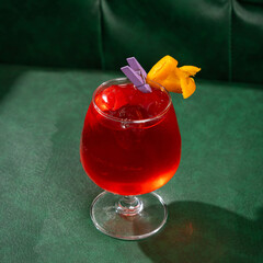 Clarified Negroni cocktail on a green sofa background