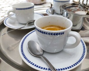 Espresso coffee in a white cup with saucer and spoon at home, close-up.  traditional italian...