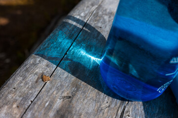 Blue water bottle on a weathered wooden table with blue transmitted light