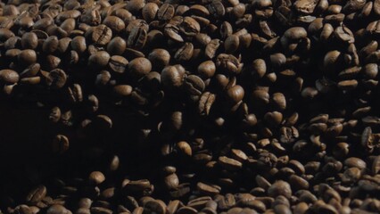 Roasted coffee beans piling up, creating a rich