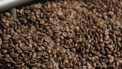 Roasted coffee beans sliding down a metal chute in