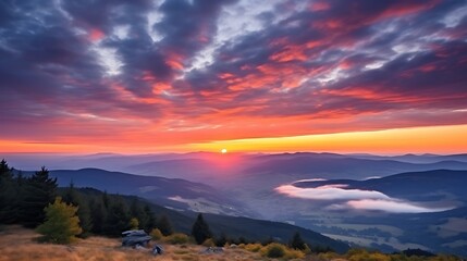 Fototapeta premium A vivid sunrise with brilliant orange and pink clouds scattered across the sky, the Carpathian ranges in sharp silhouette, sunbeams breaking through the clouds and casting rays across the land.