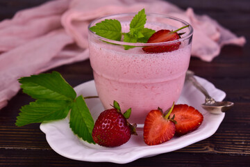 Strawberry pudding in a glass on a dark wooden background.

