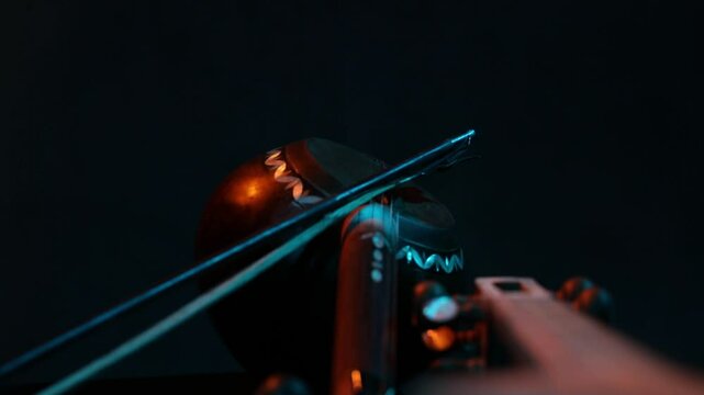 Extreme macro shot of a traditional ethnic stringed instrument. The camera slowly reveals details of the tuning pegs, strings, and fretboard with moody lighting.
