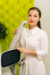 Vertical portrait of beautician posing with new modern mesotherapy apparatus, holding handles,...