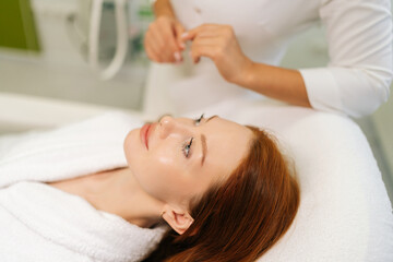Unrecognizable beautician reassuring female patient before starting beauty or wellness treatment in modern bright clinic, taking care and creating relaxing atmosphere. Concept of rejuvenation skincare