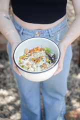 Woman holding a white bowl with refreshing green vegetable-based food under natural daylight. A fresh, vibrant, and healthy lifestyle scene that evokes wellness, nature, and clean eating.