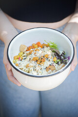 Woman holding a white bowl with refreshing green vegetable-based food under natural daylight. A fresh, vibrant, and healthy lifestyle scene that evokes wellness, nature, and clean eating.