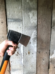 Hand holds axe near wooden wall for chopping activity