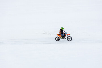 A man is riding a dirt bike on a snowy road