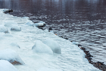 A body of water with ice on the shore