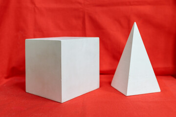 Two white shapes, one square and one triangular, are on a red background