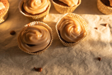 Two muffins with glossy icing in the warm light. The icing appears creamy and freshly applied.
