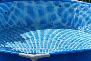 Close-up of an empty blue pool with a typical pattern. Sunlight casts shadows on the interior...