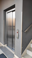 Modern elevator with closed stainless steel doors in stairwell area,illustrating accessibility,urban infrastructure,vertical mobility,interior architecture and building convenience