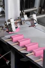 Close-Up of Pink Ice Cream Popsicles on Industrial Production Line – Frozen Dessert Manufacturing