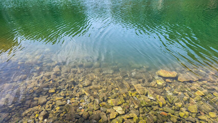 Clear, clean water: beautiful rocks and pebbles at the bottom of a calm lake in the small French town of Le Soler