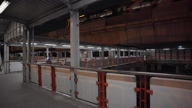 Modern BTS Mo Chit Station platform in Bangkok with orange safety barriers, white screen doors, and train in motion. Located near Chatuchak Park in Thailand's capital.