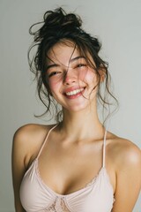 A smiling Japanese woman, wearing pastel pink cloth, expresses joy in her portrait, complemented by a white background that creates an inviting mood.