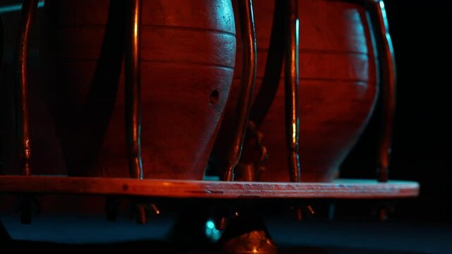 A cinematic close-up of Latin timbale drums under dramatic red and blue stage lighting. The camera tilts up and pulls focus to an atmospheric, blurry shot.