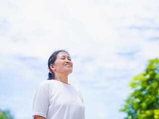 Happy Asian senior woman standing smile in park holiday for concept healthy lifestyle and meditation. Elderly care female active exercise enjoy feeling yoga, health care, freedom. Wellness mindfulness