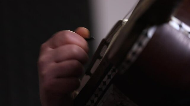 Close-up of a musician's hands playing the Tar, a traditional Persian string instrument. Shallow depth of field focuses on the fretwork during an intimate cultural music performance.