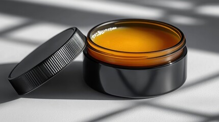 Amber Glass Jar of Orange Cosmetic Cream or Balm with Black Lid Skincare Product