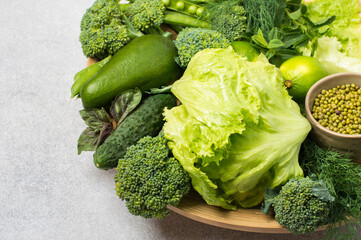 Fresh green organic vegetables assorted on a plate, free space for copy. Healthy lifestyle, detox, flat lay.