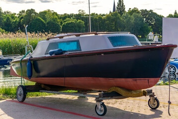 motorboat on a transport trolley at a marina quay, with greenery and other boats in the background.