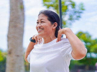 Happy asian senior woman active stretching use smart watch fitness tracker for health care in park....