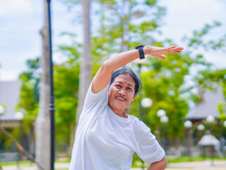 Happy asian senior woman active stretching use smart watch fitness tracker for health care in park....