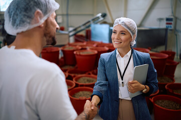 Obraz premium Happy company owner handshaking with her worker in food processing plant.
