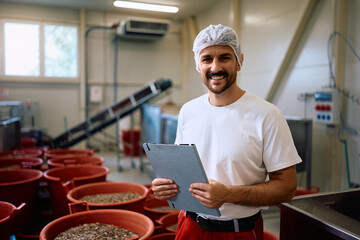 Happy quality control inspector grading quality of sunflower seeds in factory and looking at camera.
