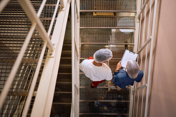 Above view of quality control manager and factory plant employee on the staircase.