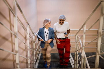 Happy worker and food factory manager walking up the stairs.