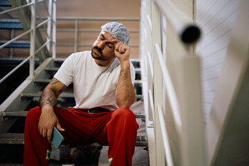 Male worker feeling tired after hard work shift in a factory.