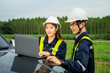 Engineers in reflective vests reviewing plans under evening sky.