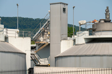 Biogas production facility closeup. Stairways for maintenance workers to get to the top of the equipment. Blue sky.