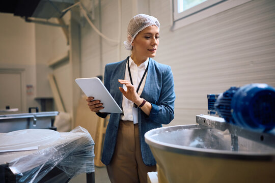 Food factory manager using digital tablet while motoring production process at the facility.