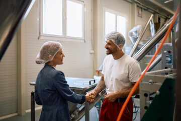 Happy female manager greeting a worker at food processing plant.