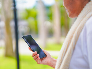 Happy senior woman enjoying using smartphone for online shopping, research browser, chat communication or checking fitness tracker after exercise in park holiday. Elderly use technology in lifestyle 