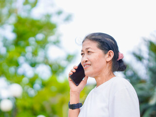 Happy senior woman enjoying using smartphone for video call, research browser, chat communication or calling to family after exercise in park holiday. Elderly use technology in lifestyle. Healthcare 
