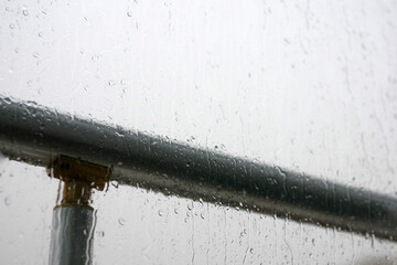 Raindrops falling on the balcony glass, raindrops sliding off the glass,