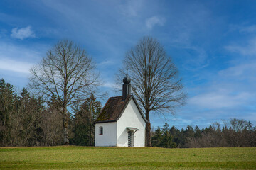 Fototapeta premium Small white chapel in a green landscape in the winter