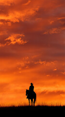 Fototapeta premium a cowboy on horseback on a hilltop at sunset