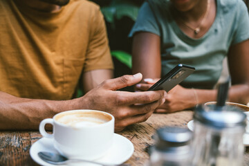 Closeup of couple using smartphone sitting in coffee shop