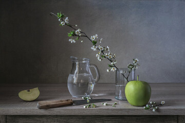 Still life with an apple and a blooming cherry twig.