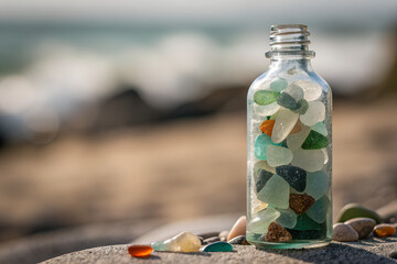 Colorful Sea Glass in a Bottle on a Sandy Beach with Ocean in Background
