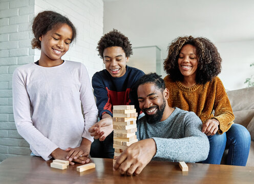 Portrait of a happy african american family at home, having fun playing wooden brick challenge game, playing board game jenga at home